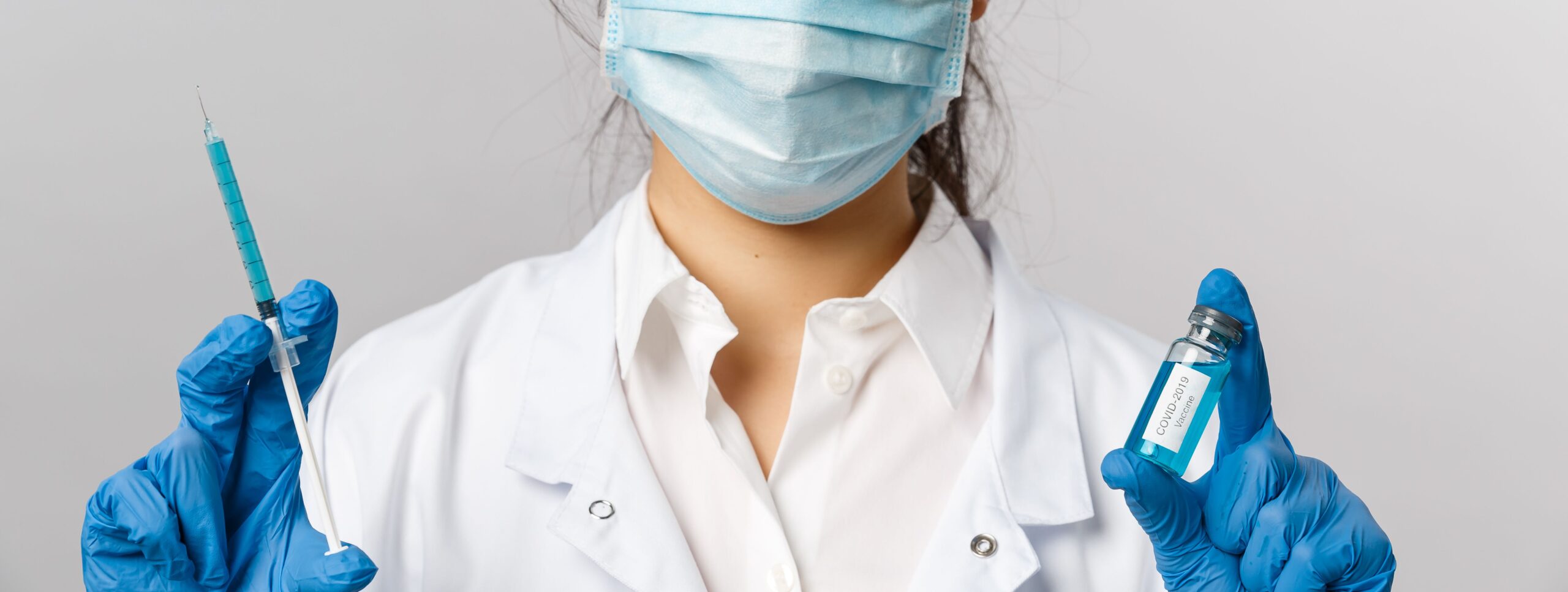 Close-up of healthcare worker with syringe and COVID-19 vaccine vial, emphasizing safety and prevention.